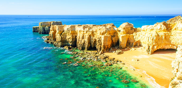 sunny image of Algarve coast with clear blue waters